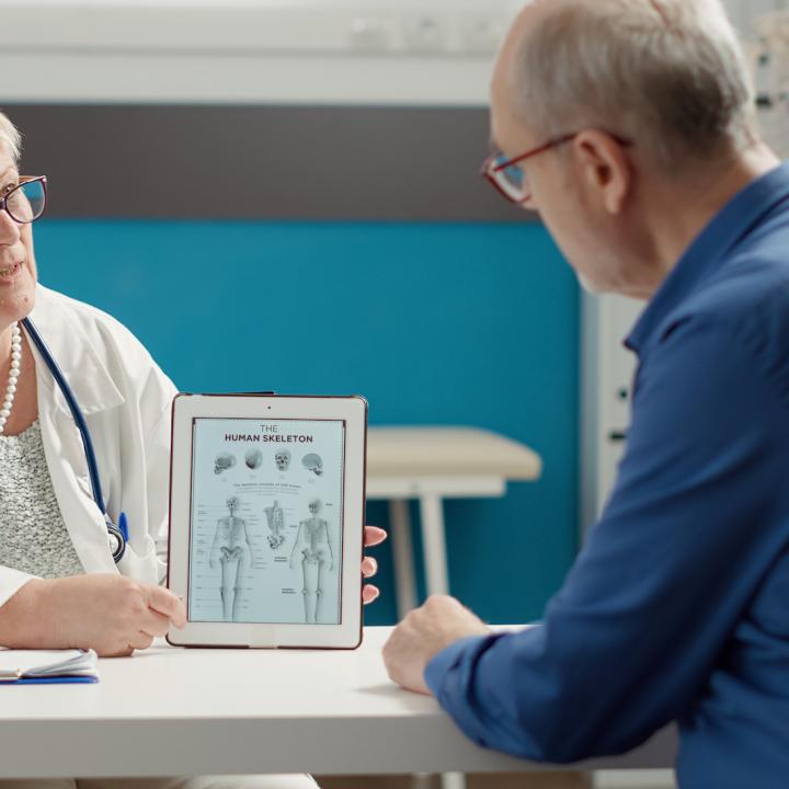 Nurse practitioner showing tablet computer to patient with diagnosis information