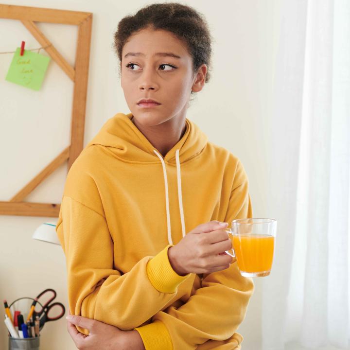 Sad teenage girl holding glass of orange juice