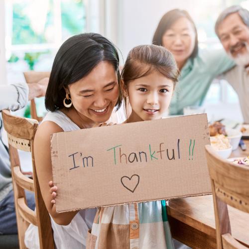 Happy Asian American girl with family holding a sign that says I'm Thankful