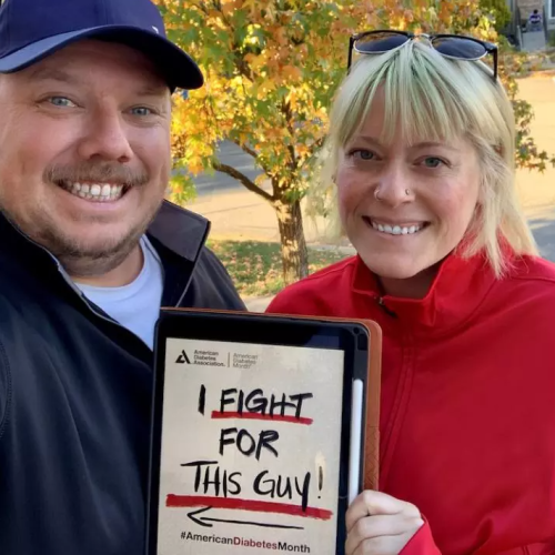 Husband and wife holding up sign that says I fight for this guy