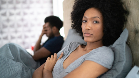 A couple look unhappy while in bed