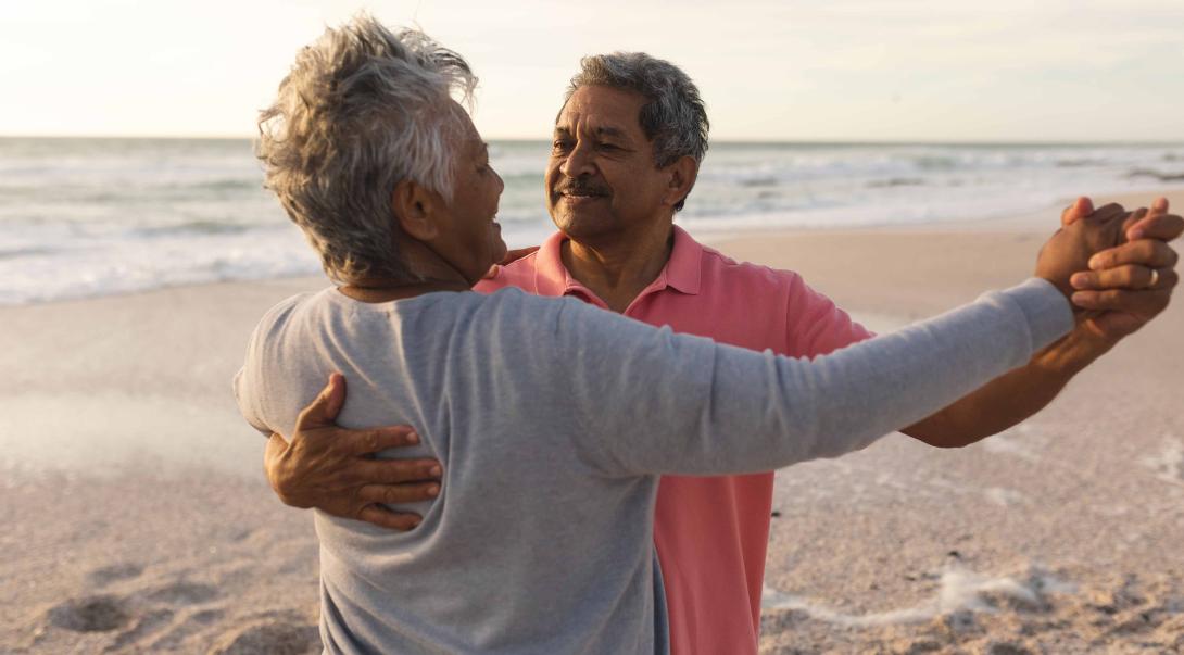 Senior latino husband and wife dancing on beach